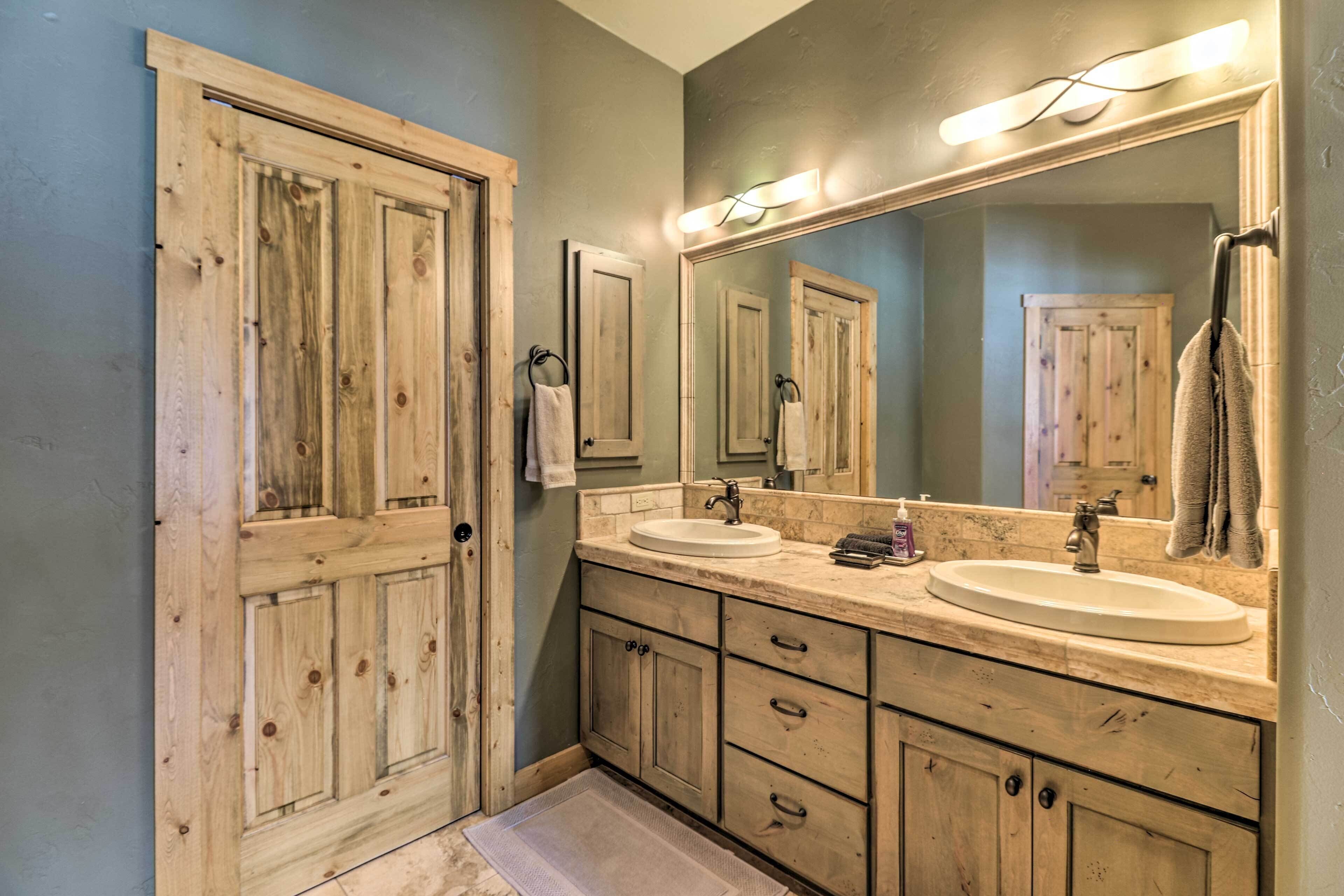 A bathroom with wooden cabinets, a large mirror, and two sinks.