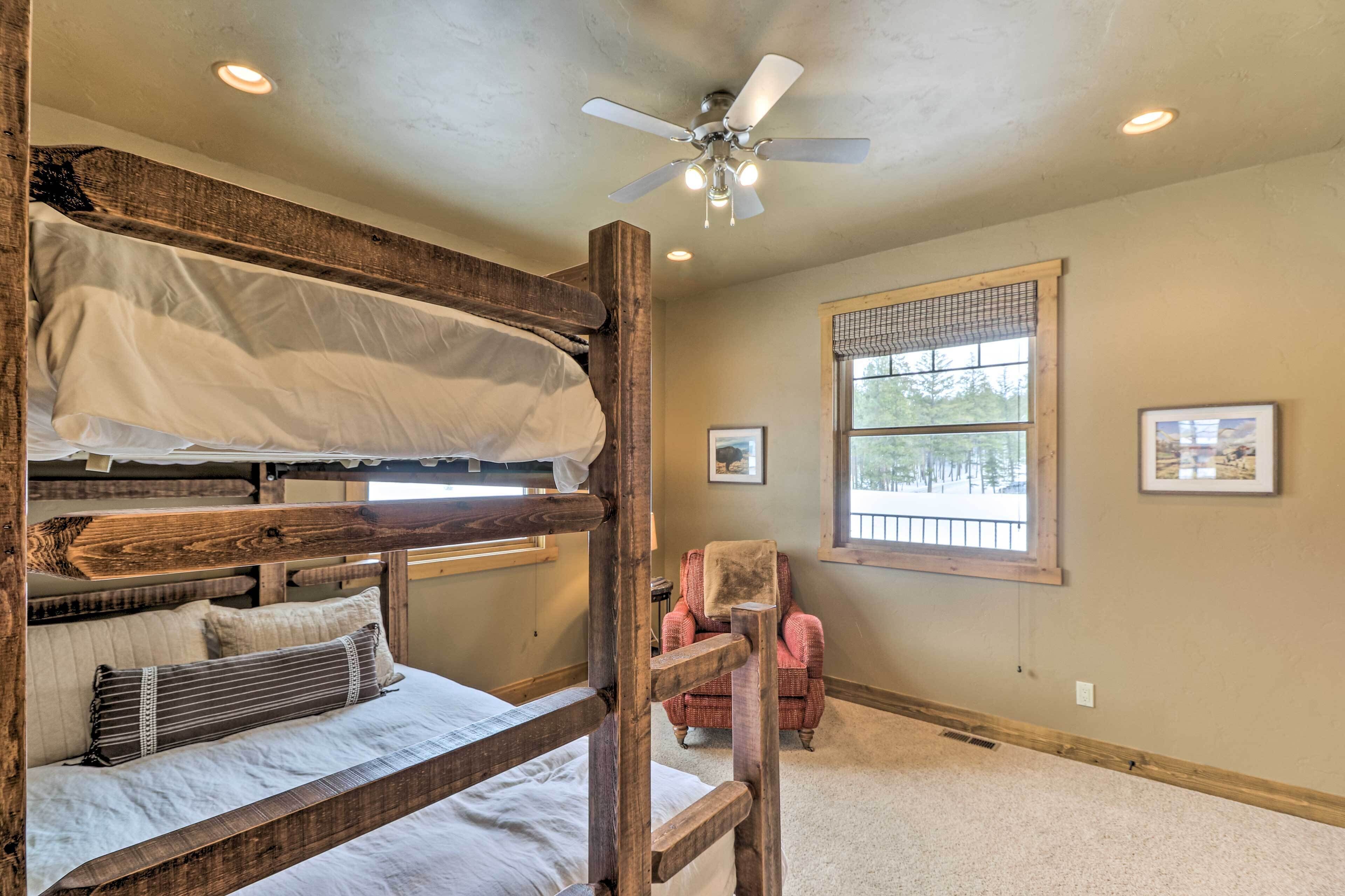 A bunk bed room with a ceiling fan, a window with blinds, and a chair.