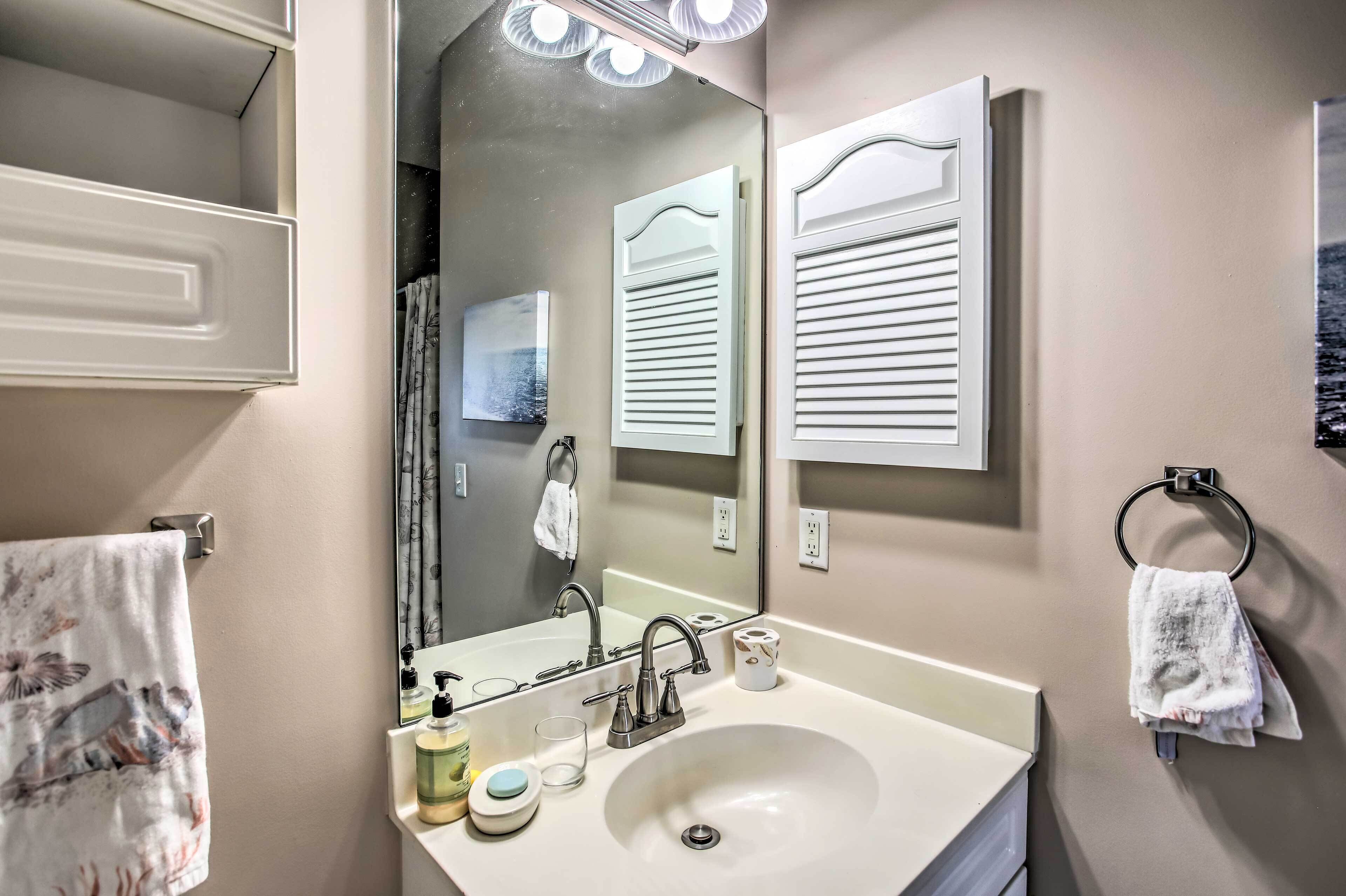 A bathroom with a sink, mirror, towel rack, and a towel with a floral pattern.
