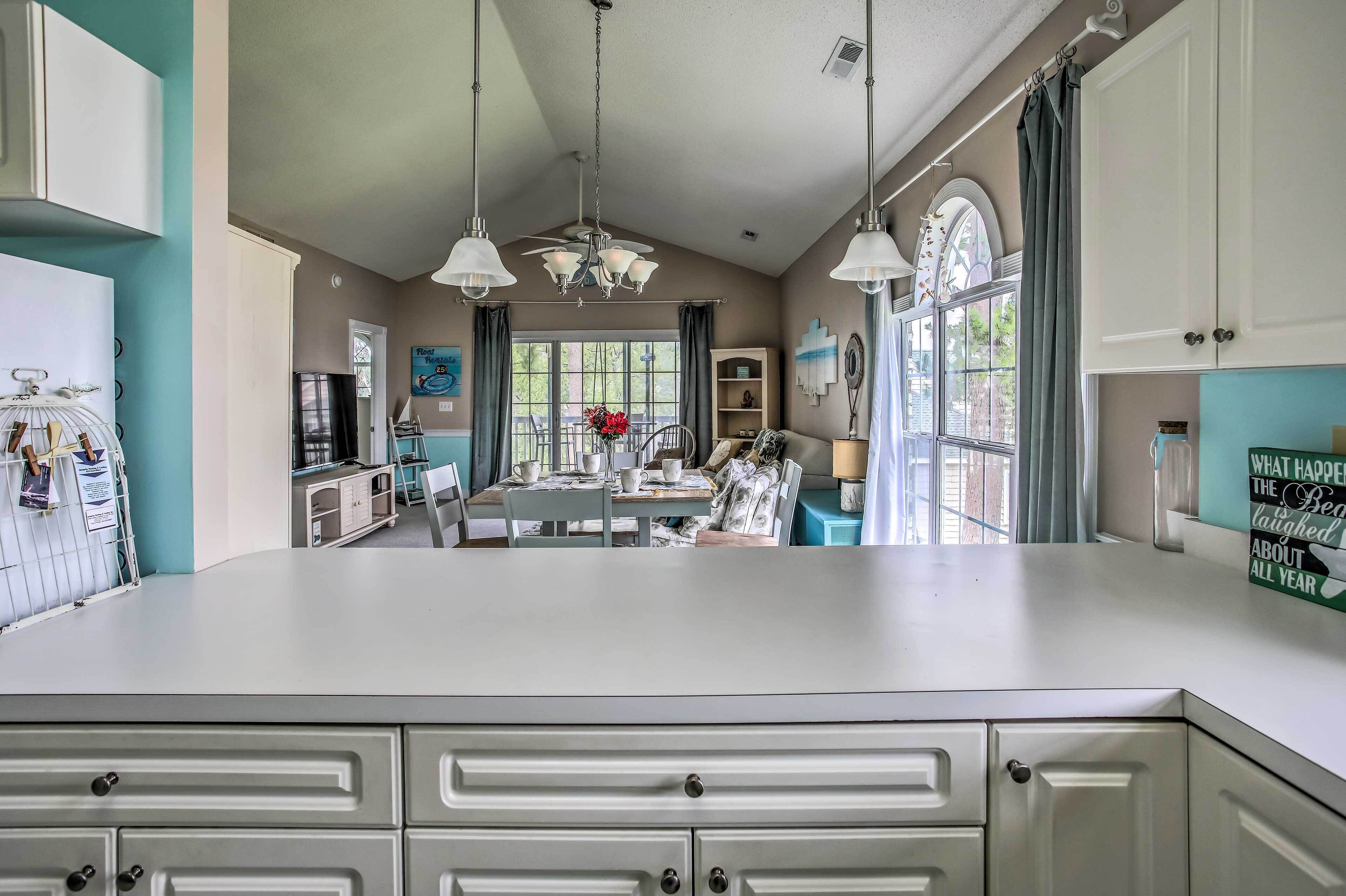 A spacious kitchen with a large island, pendant lighting, and a view of the outdoors through large windows.