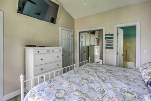 A bedroom with a bed, dresser, and a TV mounted on the wall.