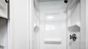 A white bathroom with a shower door, a sink, and a mirror. - Cozy Hampton Cottage w/ BBQ - Walk to Ocean! (Hampton)