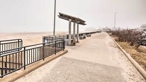 A pathway with a metal railing, a lamp post, and a concrete structure. - Cozy Hampton Cottage w/ BBQ - Walk to Ocean! (Hampton)