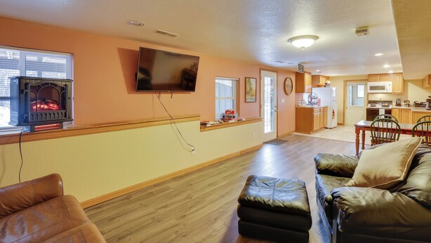 A living room with a fireplace, a television, and a kitchen in the background. - 5 Mi to Terry Peak Slopes: Quiet Apt w/ Patio! (Lead)