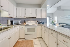A modern kitchen with white cabinets, a built-in oven, a microwave, and a gas stove.