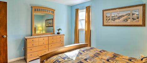 Ein Schlafzimmer mit einem Bett, einem Schminktisch, einem Spiegel und einem gerahmten Bild an der Wand.