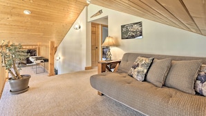 Ein gemütliches Wohnzimmer mit Holzboden, einer Couch, einer Lampe und einem Blumentopf.