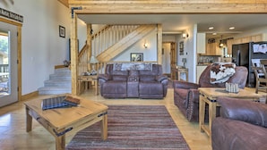 Ein geräumiges Wohnzimmer mit braunem Ledersofa, einem Holztisch und einer Treppe, die zu einer oberen Ebene führt.