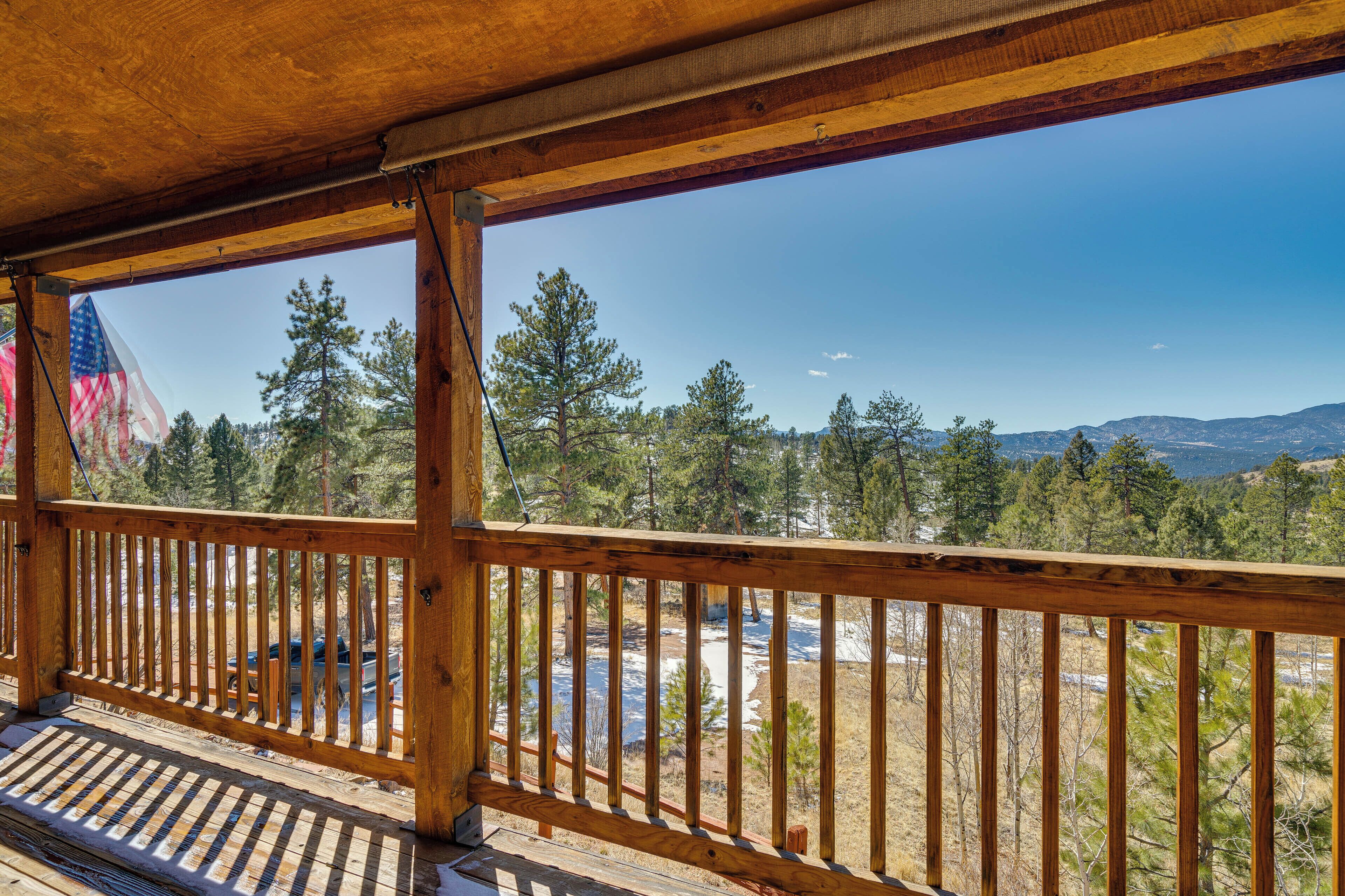 A wooden deck with a view of a river, trees, and mountains.