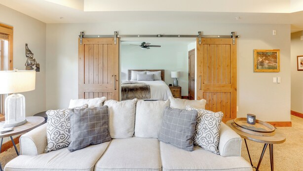 A modern living room with a sofa, a coffee table, and a large sliding door leading to a bedroom. - Half-mi to Payette Lake: Dtwn Mccall Condo! (McCall)