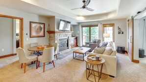A living room with a fireplace, a dining area with chairs, a sofa, and a ceiling fan. - Half-mi to Payette Lake: Dtwn Mccall Condo! (McCall)