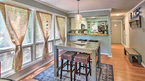 A kitchen with a glass-top table, wooden stools, and a hanging light fixture. - Mount Ida Condo w/ Balcony + Resort Amenities (Mount Ida)