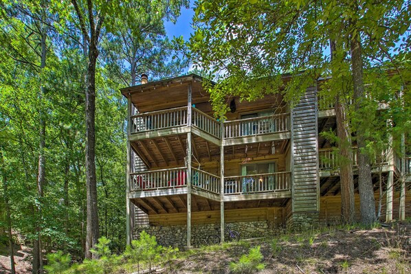 Une cabane en bois à plusieurs niveaux, dotée de balcons et entourée d’une forêt dense.