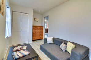 A living room with a grey sofa, a wooden dresser, and a closed white wardrobe.