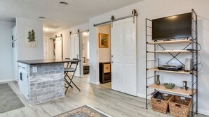 A modern kitchen with a brick island, a dining area with a table and chairs, and a TV mounted on a metal shelf. - Goldendale Vacation Rental 13 Mi to Columbia River (Goldendale)