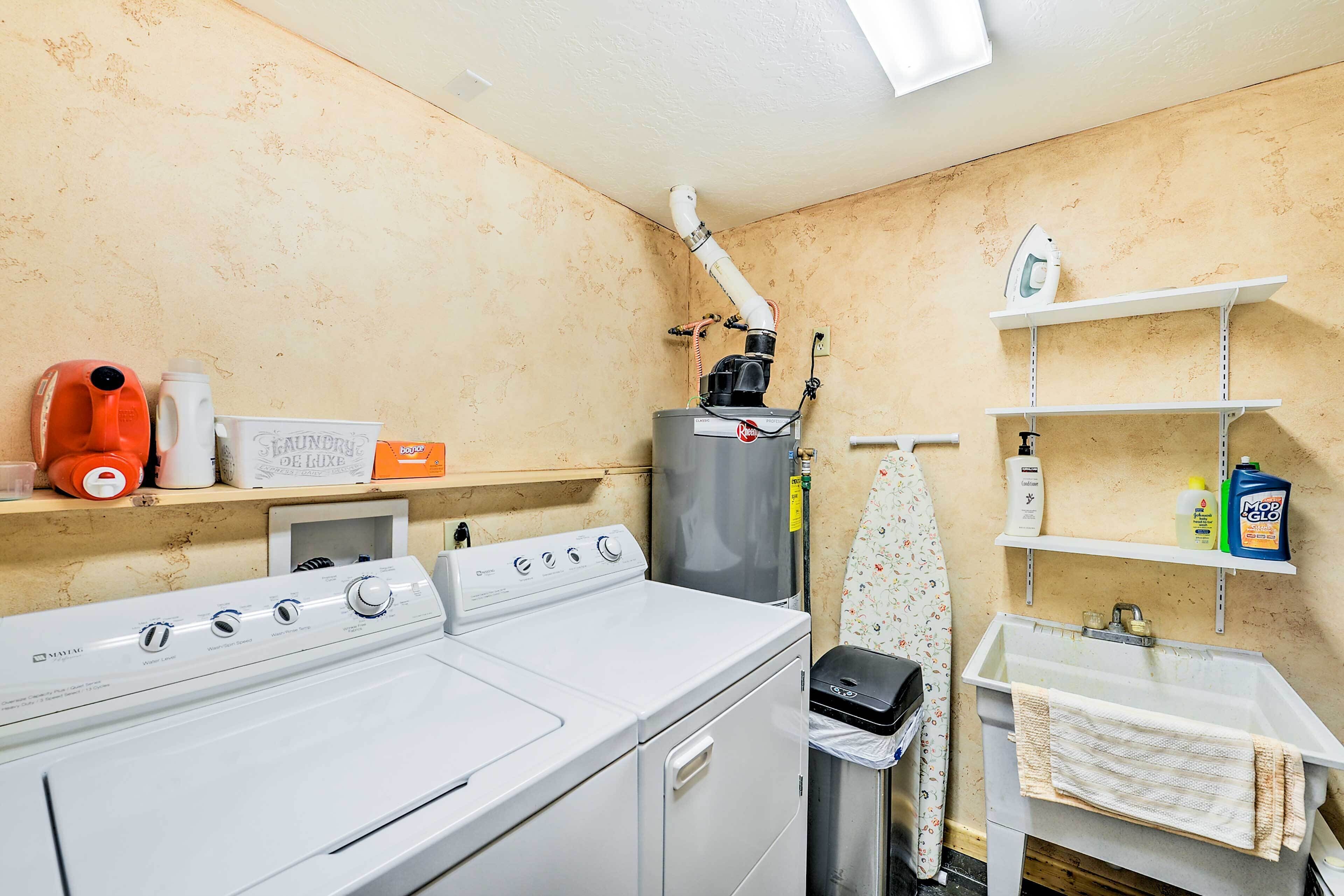 A laundry area with a washing machine, dryer, and ironing station.