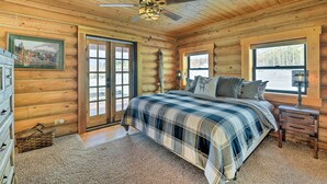 Un dormitorio tipo cabaña de madera con cama, cómoda y ventilador de techo.