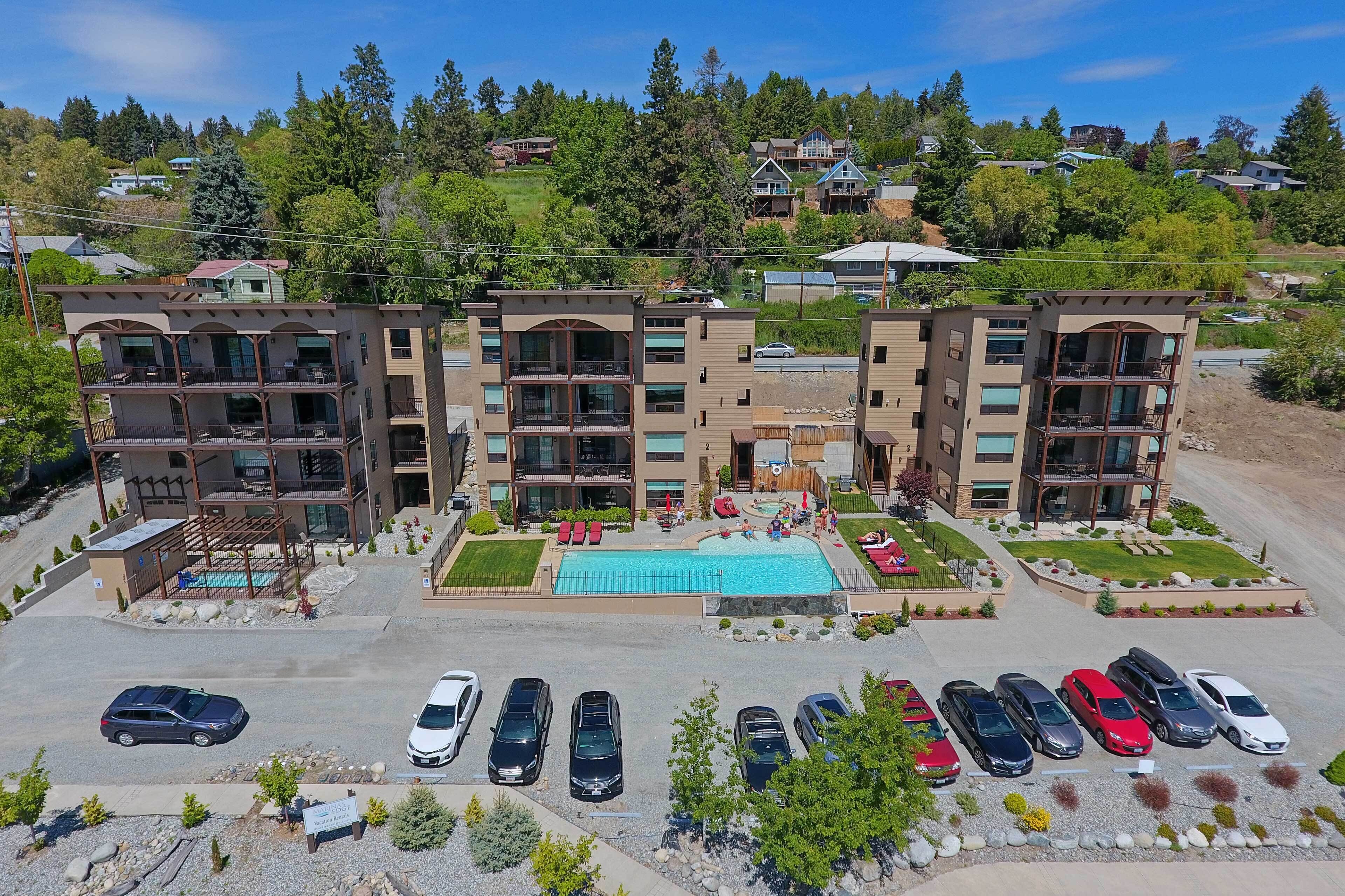Un hôtel à plusieurs étages doté d’une piscine, d’un parking et offrant une vue sur une colline où se trouvent d’autres bâtiments.