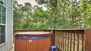 A wooden deck with a hot tub and a small stool. - Hot Tub & Wooded Views: Lakefront Blue Eye Cottage (Blue Eye)