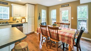 A kitchen with white cabinets, a dining table with plaid tablecloth, and a sign reading "Lakefront Lodge". - Hot Tub & Wooded Views: Lakefront Blue Eye Cottage (Blue Eye)