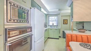 A compact kitchen with a built-in oven, a microwave, and a refrigerator. - Retro St Pete Home w/ Private Heated Pool (St. Petersburg)