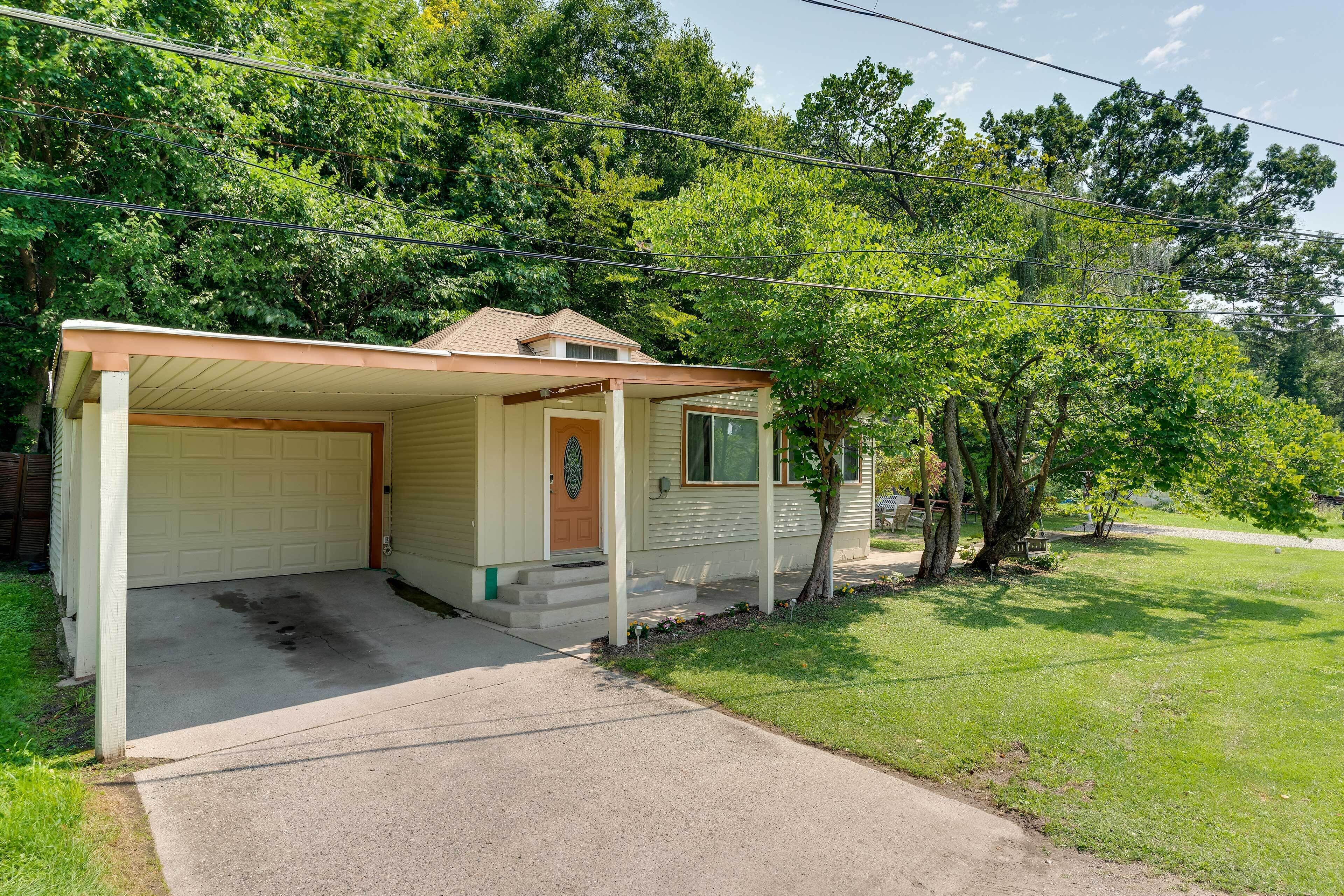 A single-story house with a garage, a covered porch, and a lawn.