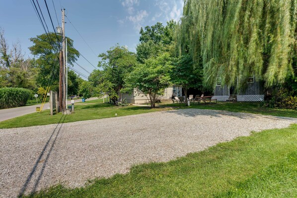 A residential area with a gravel driveway, a wooden fence, and a large weeping willow tree.