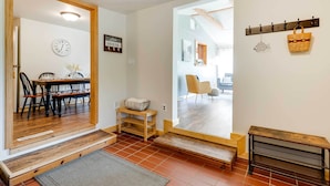 A modern interior with a wooden dining table, chairs, and a bench. There is a wall clock and a sign that reads "Live House." - Lakeside Indiana Vacation Rental Near Fort Wayne! (Churubusco)