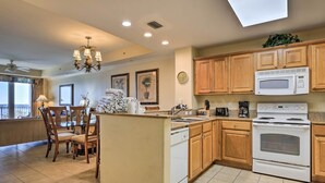 A kitchen with wooden cabinets, a white stove, and a dining area with chairs and a table.