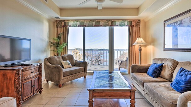 A living room with a television, two sofas, a coffee table, and a balcony with a view.