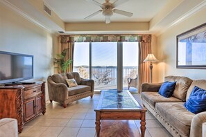 A living room with a television, two sofas, a coffee table, and a balcony with a view. - 1 Mi to Disney: Lakefront Condo w/ Pool Access! (Orlando)