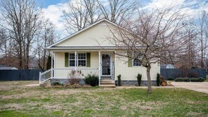 A single-story house with a front porch, a small tree, and a 'WELCOME' sign. - Single-story Manchester Home Close to Parks! (Manchester)