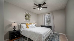 A bedroom with a bed, nightstands, a ceiling fan, a window with curtains, and a rug. - Single-story Manchester Home Close to Parks! (Manchester)