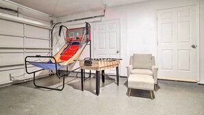 A room with a basketball hoop, a table with a basketball, and a chair. - Lovely Lauderhill Retreat < 12 Mi to Beach! (Lauderhill)