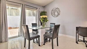 A dining area with a glass table surrounded by four chairs, a vase with flowers, and a wall art piece. - Lovely Lauderhill Retreat < 12 Mi to Beach! (Lauderhill)