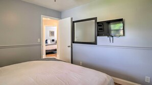 A bedroom with a bed, a ceiling fan, a wall-mounted TV, and a door leading to another room. - Lovely Lauderhill Retreat < 12 Mi to Beach! (Lauderhill)