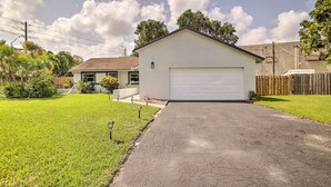 A single-story house with a garage, a well-maintained lawn, and a paved driveway. - Lovely Lauderhill Retreat < 12 Mi to Beach! (Lauderhill)
