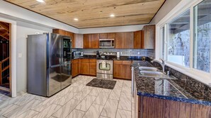 A modern kitchen with wooden cabinets, stainless steel appliances, and a large window providing a view.
