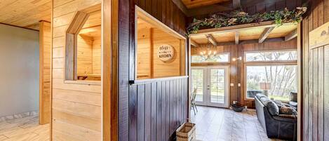 A wooden interior with a kitchen area, a dining space, and a view through a glass door.