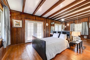 Ein Zimmer mit Holzwänden, einem Bett, einem Nachttisch und einer Wanduhr.