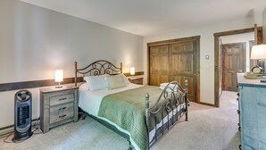 Un dormitorio ordenado con cama, mesitas de noche, un calentador y una puerta de madera.