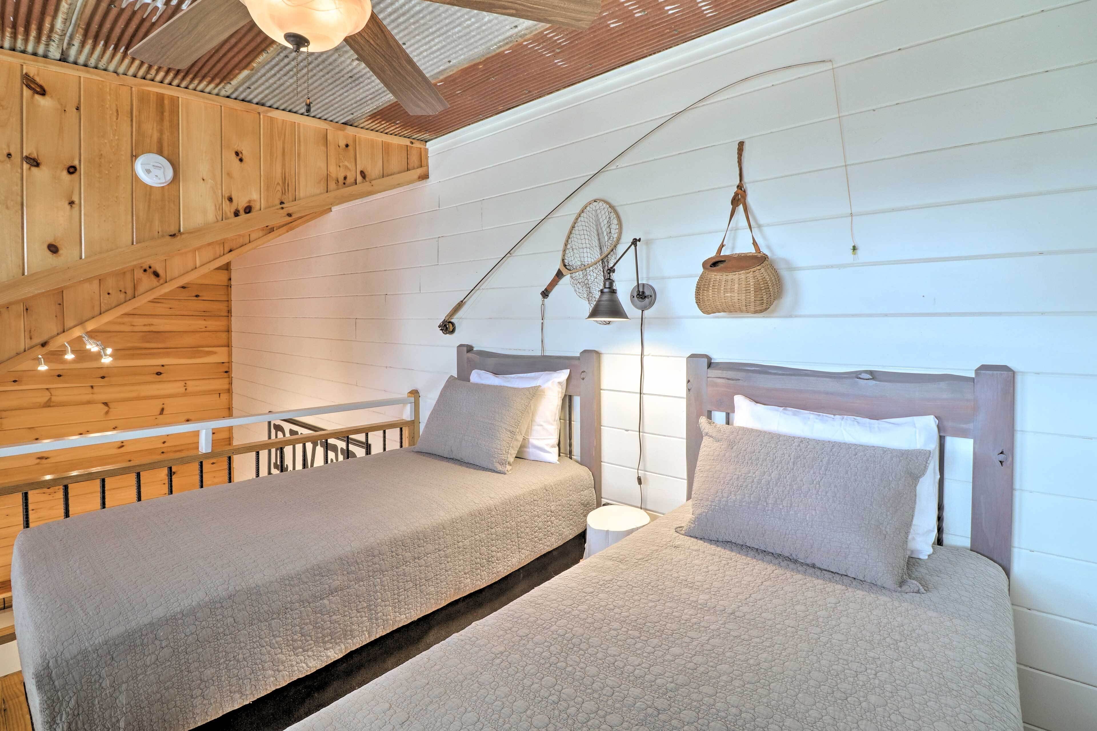 A bedroom with two beds, wooden ceiling beams, a sloped ceiling, and a hanging basket.