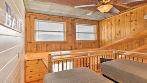 A cabin with two beds, wooden walls, a ceiling fan, and two windows with blinds. - Updated Mtn View Studio w/ Loft - Near River! (Mountain View)