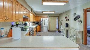 A kitchen with wooden cabinets, a refrigerator, a microwave, and a coffee maker. - Kayaks & Boat Dock: Waterfront Home in Grove (Grove)