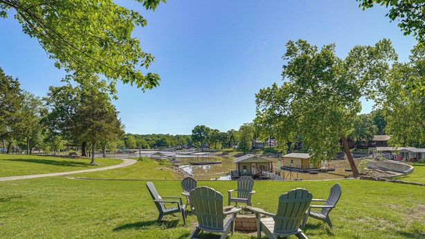 A grassy area with Adirondack chairs, a small fire pit, and a pond in the background. - Kayaks & Boat Dock: Waterfront Home in Grove (Grove)