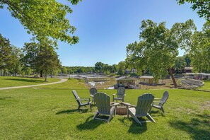 A grassy area with Adirondack chairs, a small fire pit, and a pond in the background. - Kayaks & Boat Dock: Waterfront Home in Grove (Grove)