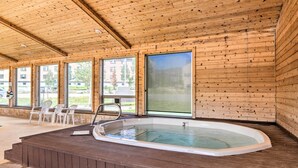 Une cabane en bois dotée d’un bain à remous, de grandes fenêtres et d’un espace salon extérieur.