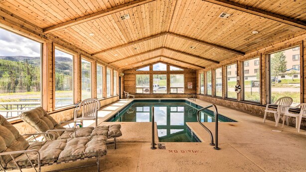 Un espace piscine doté d’un plafond en bois, de grandes fenêtres et de chaises longues.