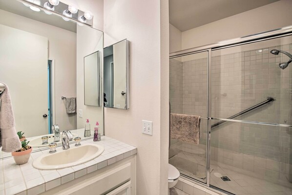 A bathroom with a sink, mirror, and glass shower enclosure.