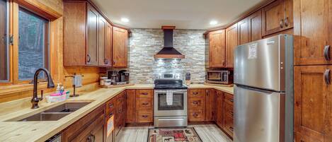 Una cocina con armarios de madera, un refrigerador de acero inoxidable, un horno y un protector contra salpicaduras de piedra.